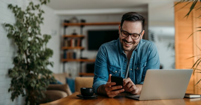 Portrait of a cheerful man using smart phone at home office
