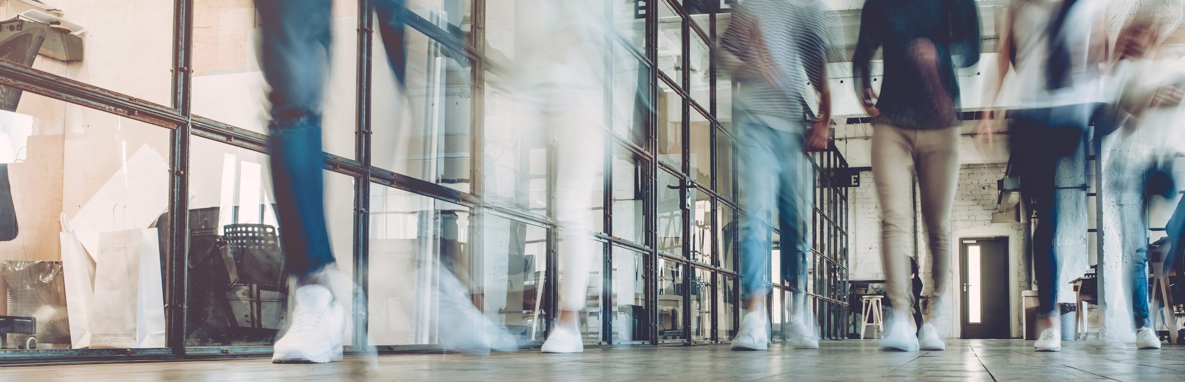 Multiracial young creative people in modern office. Successful hipster team in coworking. Businesspeople walking in the corridor of an business center. Motion blur.