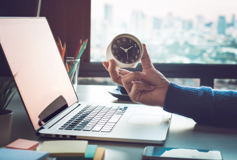 Business concepts with businessman holding clock on computer laptop