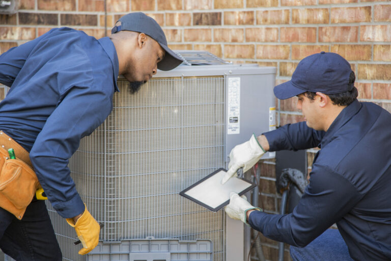Multi-ethnic team of blue collar air conditioner repairmen at work