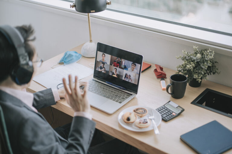 an asian chinese mid adult businessman having video conference with his colleague and business partners in the office using headset and laptop